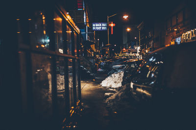 Cars parked by sidewalk at night during winter