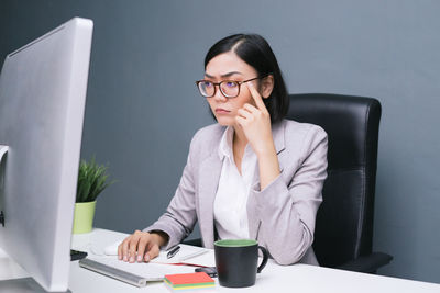 Young woman using mobile phone while sitting on table
