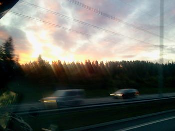 Cars on road against sky during sunset