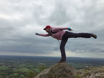 Man balancing on rock against sky