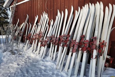 Close-up of skis on snow by fence during winter