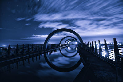 Pier over river against sky at night