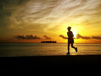 Silhouette man on beach against sky during sunset