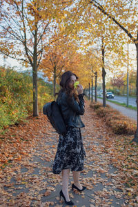 Full length of woman standing by tree during autumn