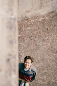 Portrait of smiling man standing by wall outdoors