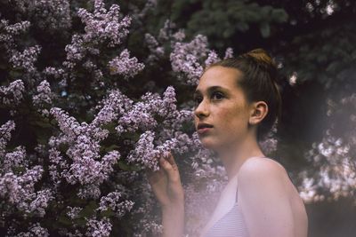 Thoughtful teenage girl looking away by flowering plants at park