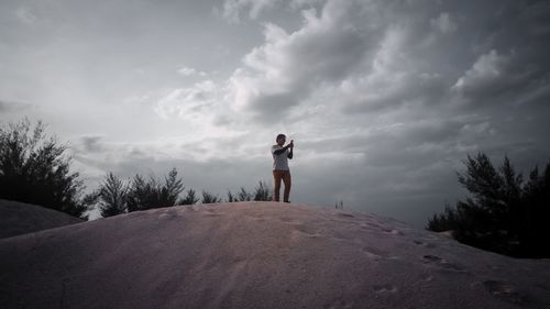 Man standing on rock against sky