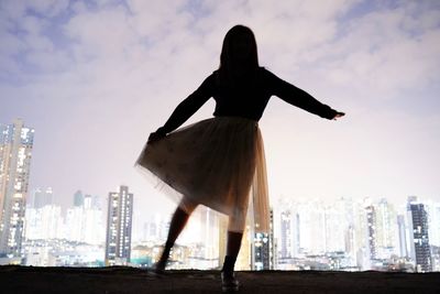 Low angle view of woman against buildings in city against sky