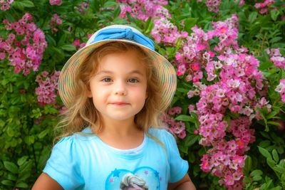 Portrait of cute girl against pink flowering plant