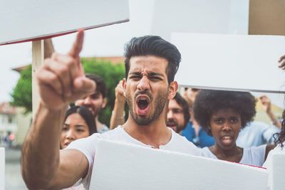 Portrait of young man with people protesting in city