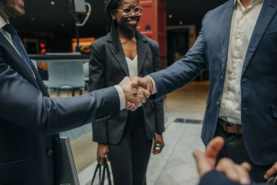 Businessmen handshaking by female colleague in hotel lounge