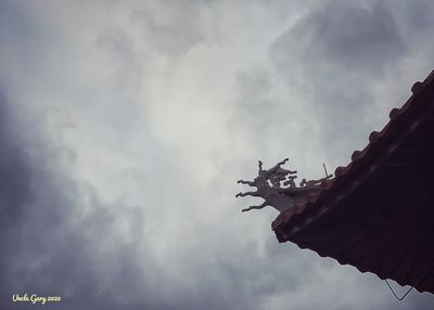 Low angle view of cross on roof against sky