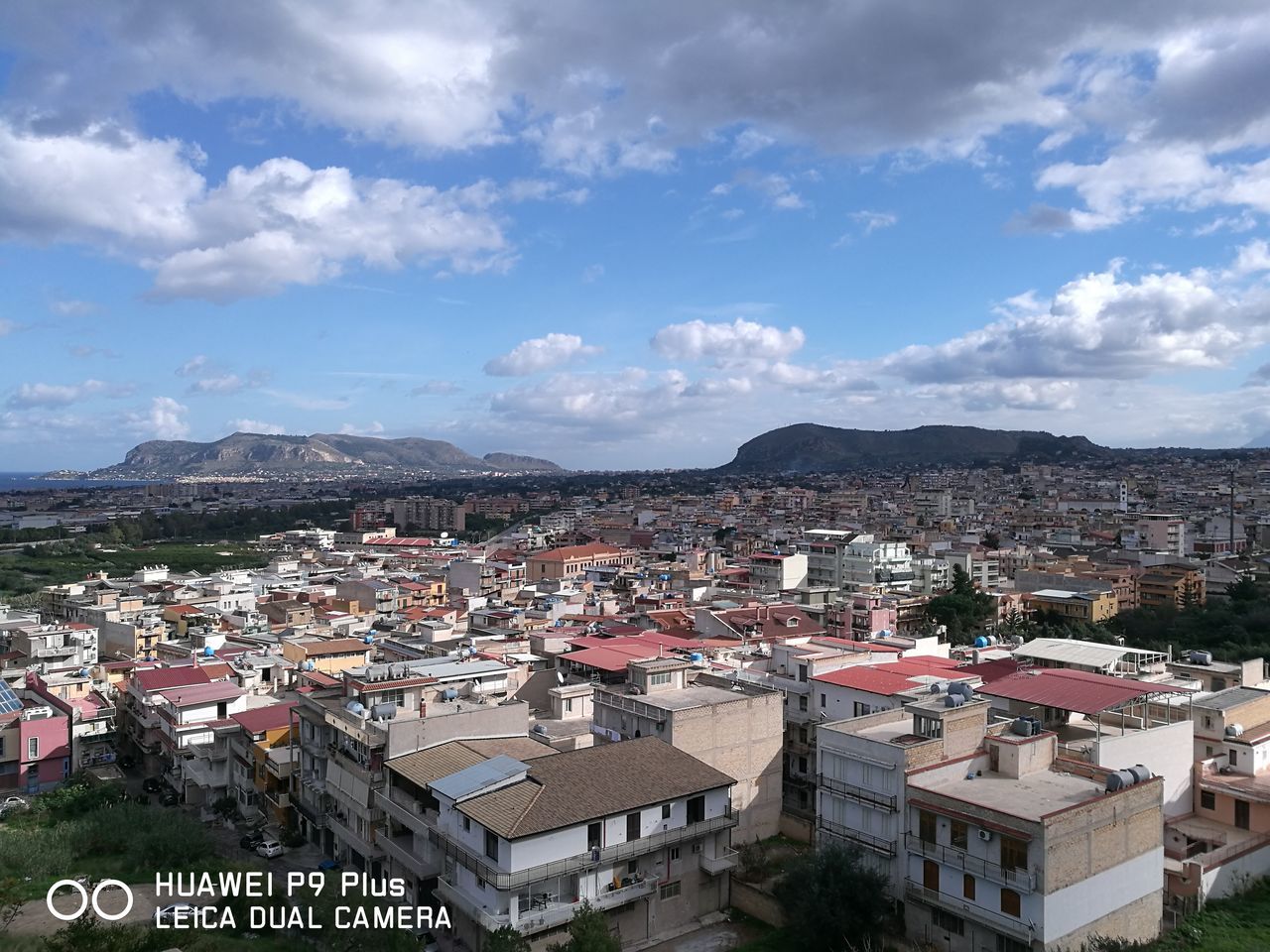 city, cityscape, architecture, building exterior, cloud - sky, high angle view, travel destinations, outdoors, sky, mountain, built structure, roof, residential building, urban skyline, day, no people