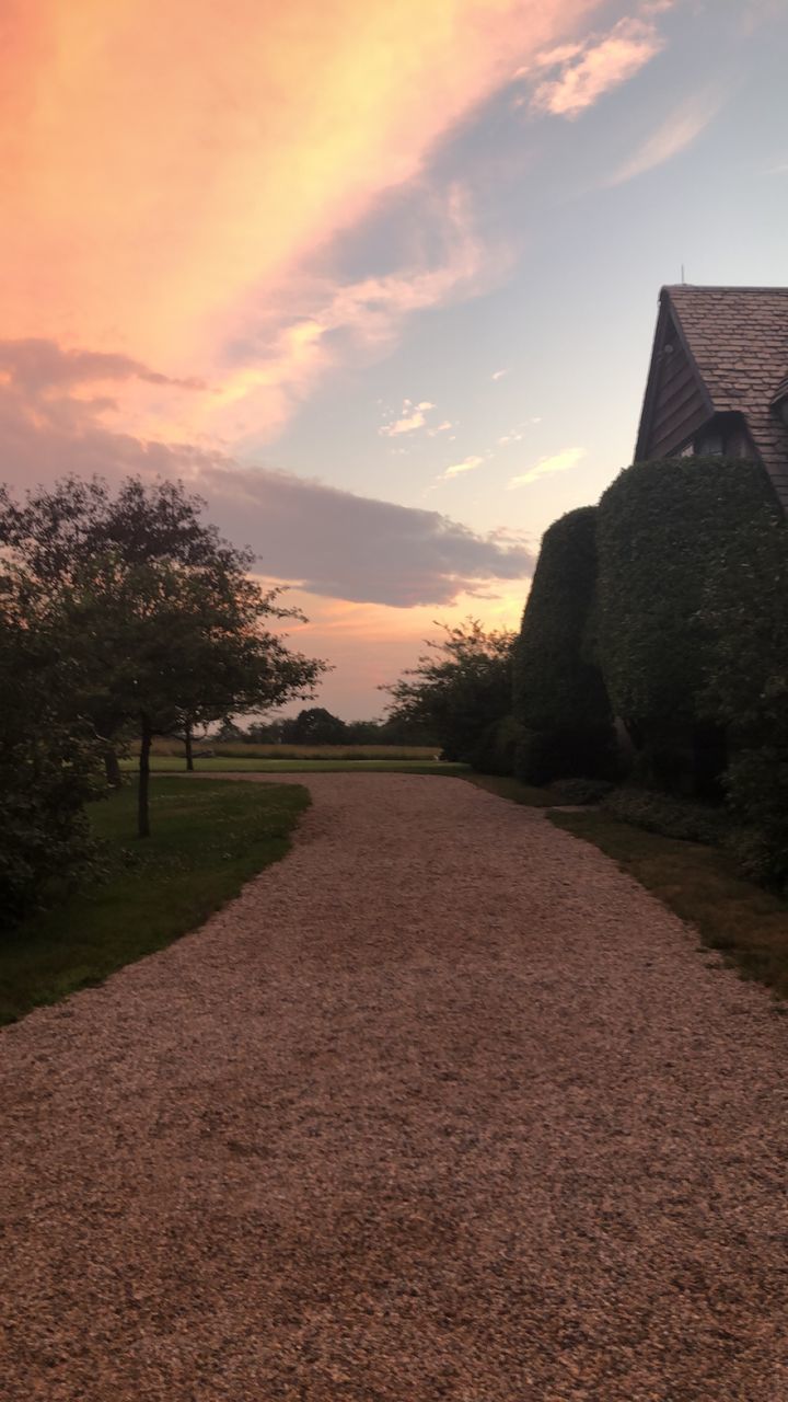 WALKWAY AMIDST BUILDINGS AGAINST SKY AT SUNSET