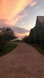 Walkway amidst buildings against sky during sunset