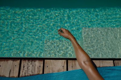 Cropped human hand against the pool