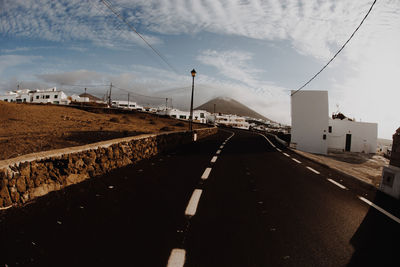 Road leading towards city against sky