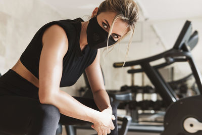 Portrait of woman wearing mask exercising at gym