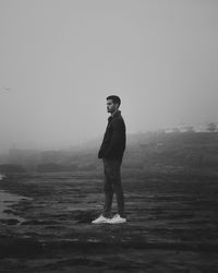 Full length of young man standing on land against sky