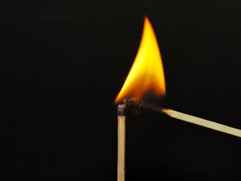 Close-up of burning matchstick against black background