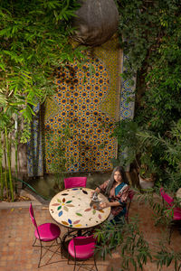 Portrait of girl sitting on table against plants