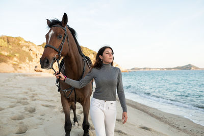 Young woman riding horse standing on beach