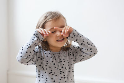 Smiling girl standing against white wall