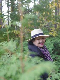 Portrait of smiling young woman against trees