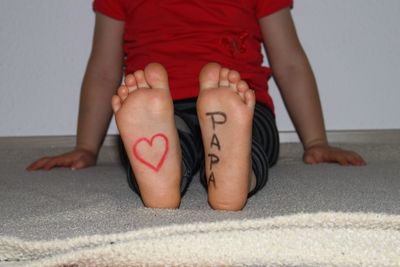 Low section of girl with text on foot sole at home