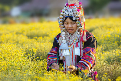 Full length of cute girl with yellow flowers on field