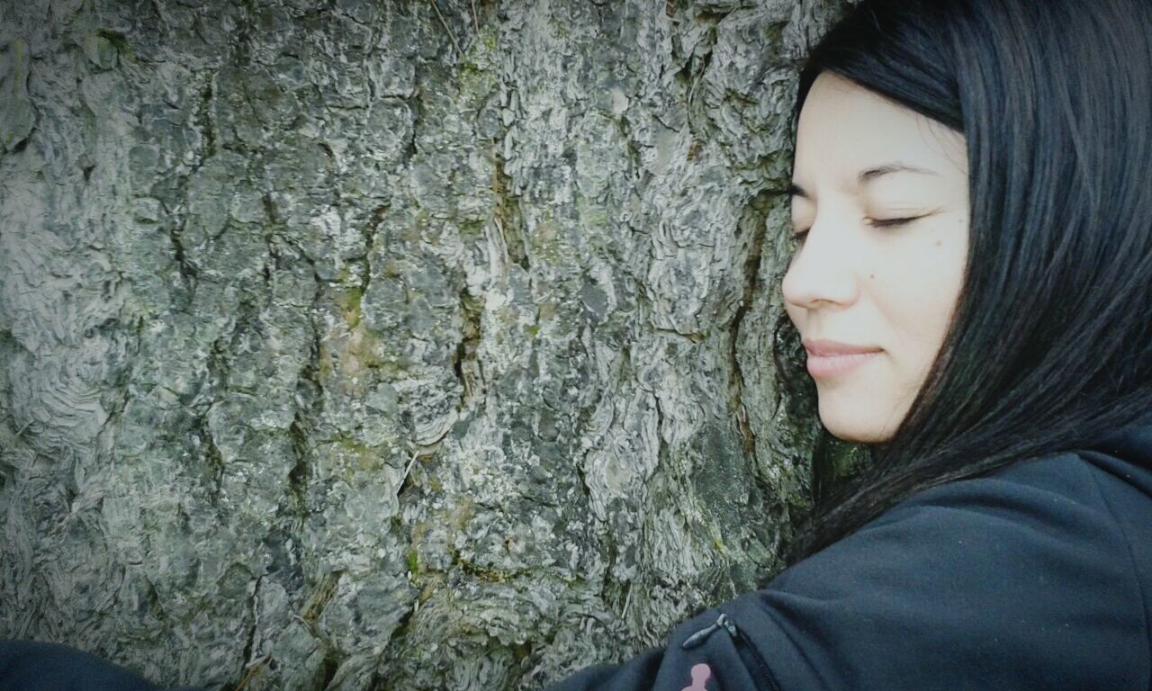 lifestyles, young adult, leisure activity, young women, person, portrait, headshot, close-up, casual clothing, front view, textured, looking at camera, tree trunk, standing, outdoors, day, long hair, human face