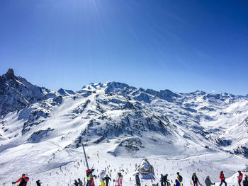 Group of people on snowcapped mountain against clear sky