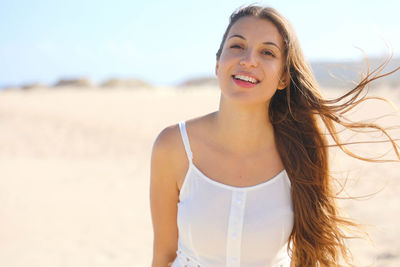 Portrait of smiling woman standing at beach