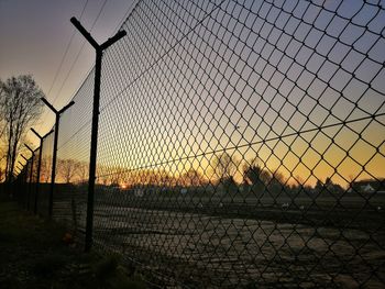 Chainlink fence against sky during sunset