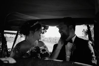 Smiling bride and groom sitting in car