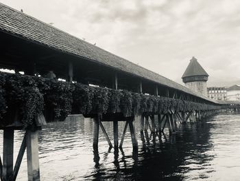 Bridge over river by buildings against sky