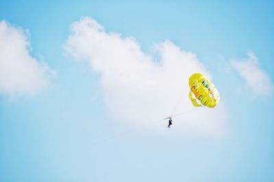 Low angle view of person parasailing against sky