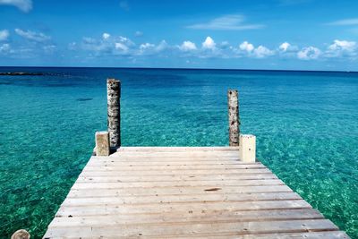 Wooden pier over sea against blue sky