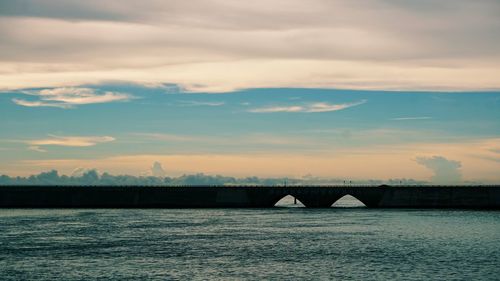 Bridge over sea against sky during sunset