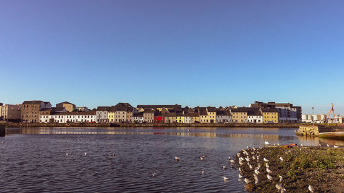 River by townscape against clear blue sky