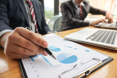 Midsection of business colleagues working on table