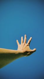 Close-up of hand against blue sky