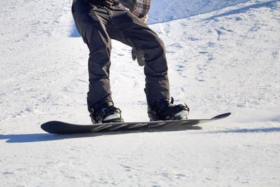 Low section of man snowboarding on snow