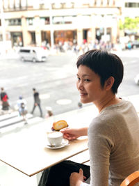 Woman holding coffee cup at cafe in city