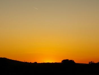 Scenic view of silhouette landscape against orange sky