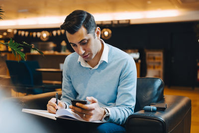 Young man using phone while sitting on chair