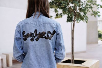 Rear view of woman with text on denim shirt