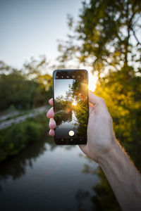 Hand holding smart phone against sky