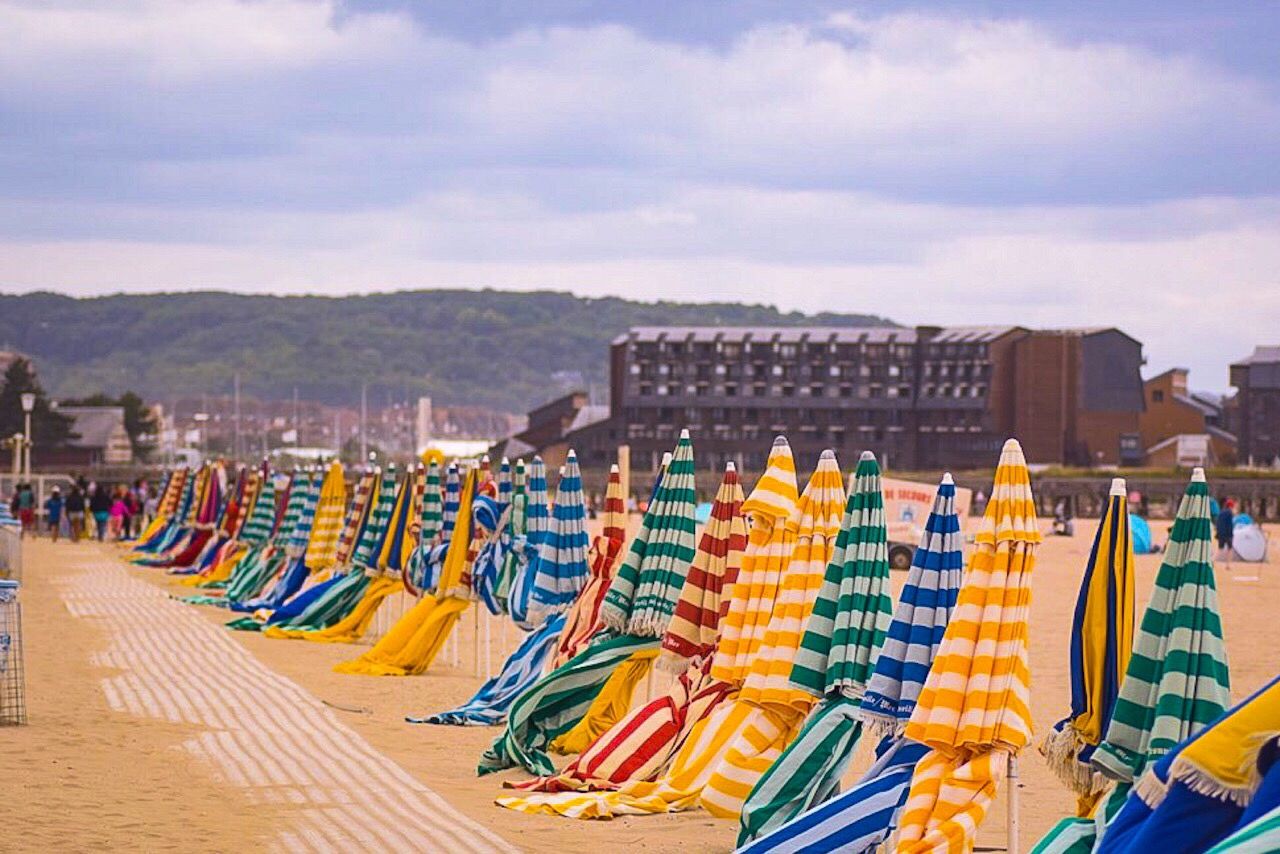 in a row, sky, multi colored, cloud - sky, summer, outdoors, sand, large group of objects, beach, no people, stadium, day