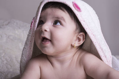 Close-up of shirtless baby girl lying on bed